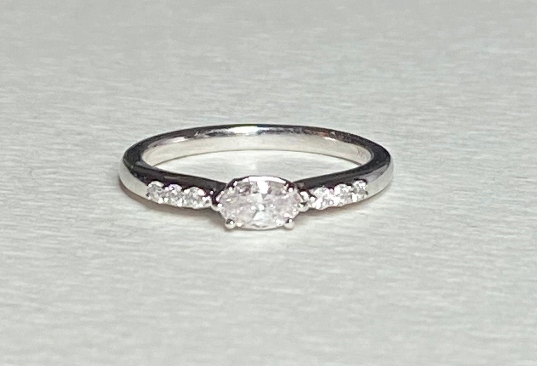 A 14k white gold band ring with a marquise-cut pink diamond and six white accent diamonds.
