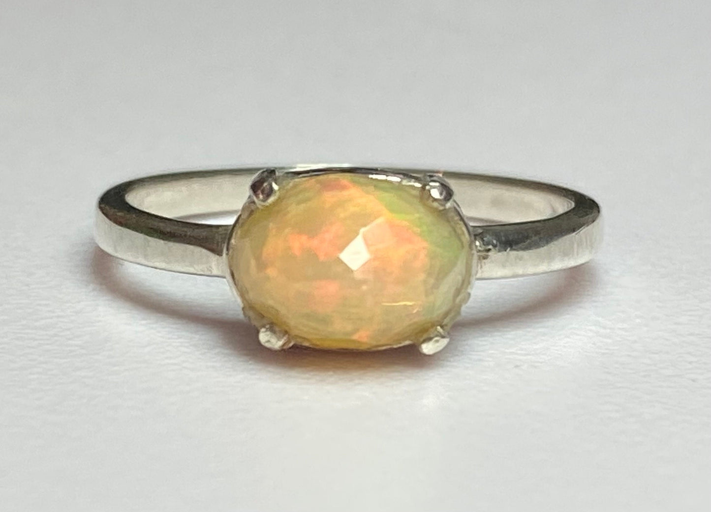 Sterling silver band ring with a faceted oval Ethiopian Wello opal.