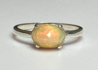 Sterling silver band ring with a faceted oval Ethiopian Wello opal.