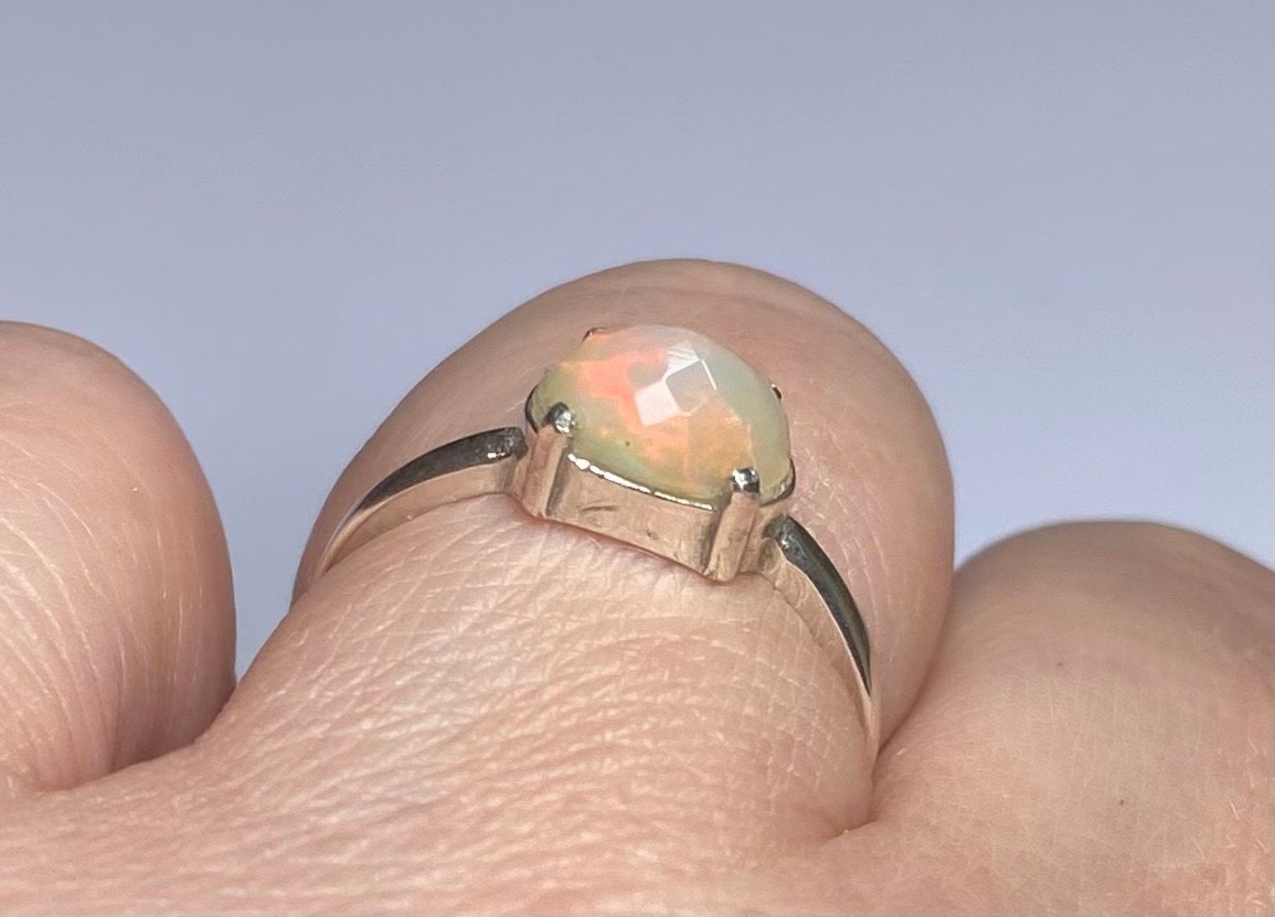 Sterling silver band ring with a faceted oval Ethiopian Wello opal.