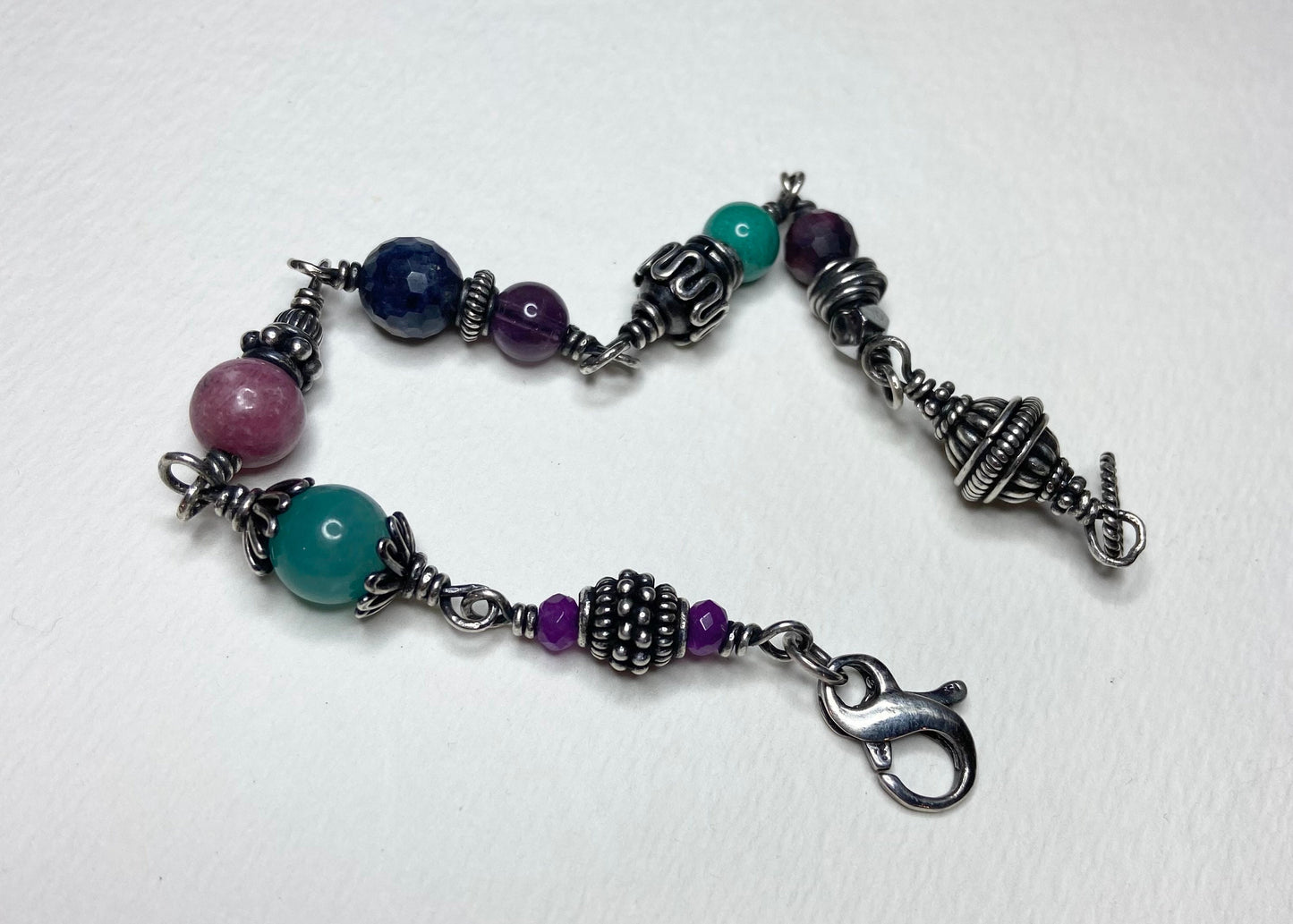 Sterling silver beaded bracelet with multi-colored gemstones and a lobster clasp.
