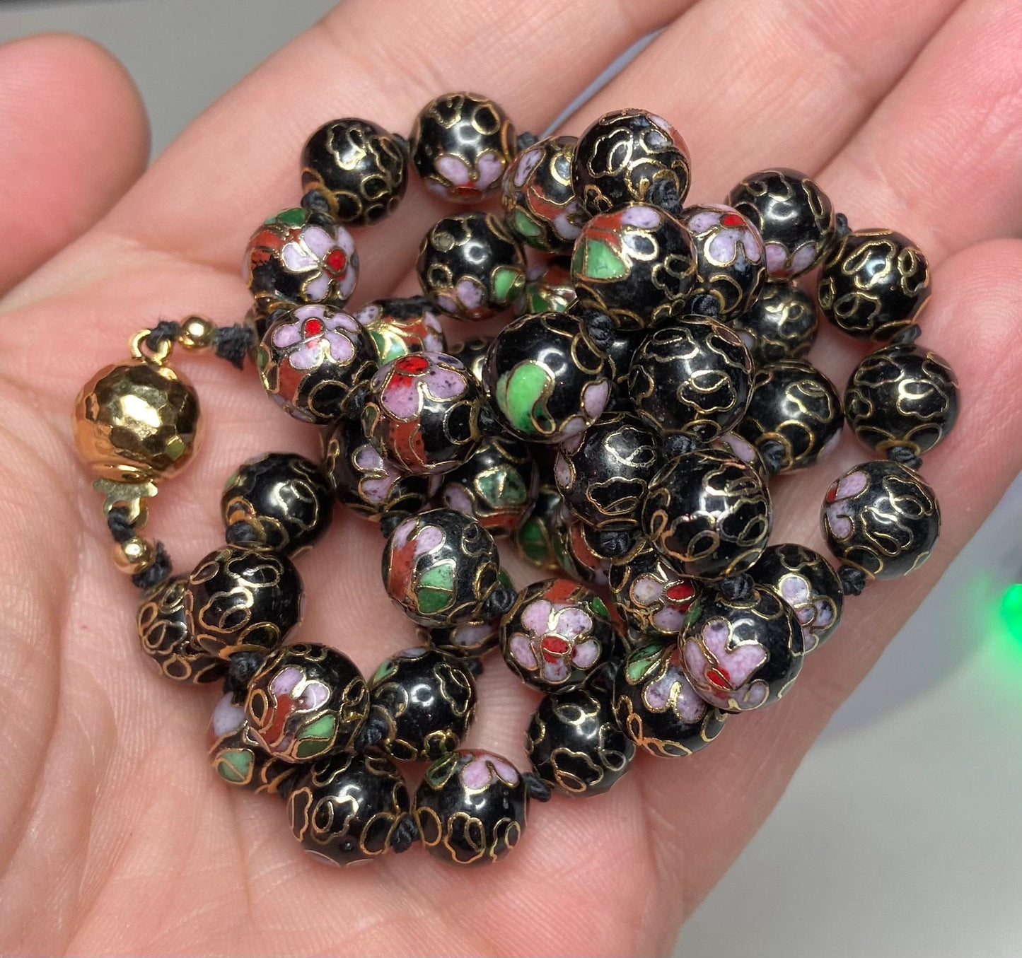 Cloisonné beaded necklace with black, pink, and gold floral designs.