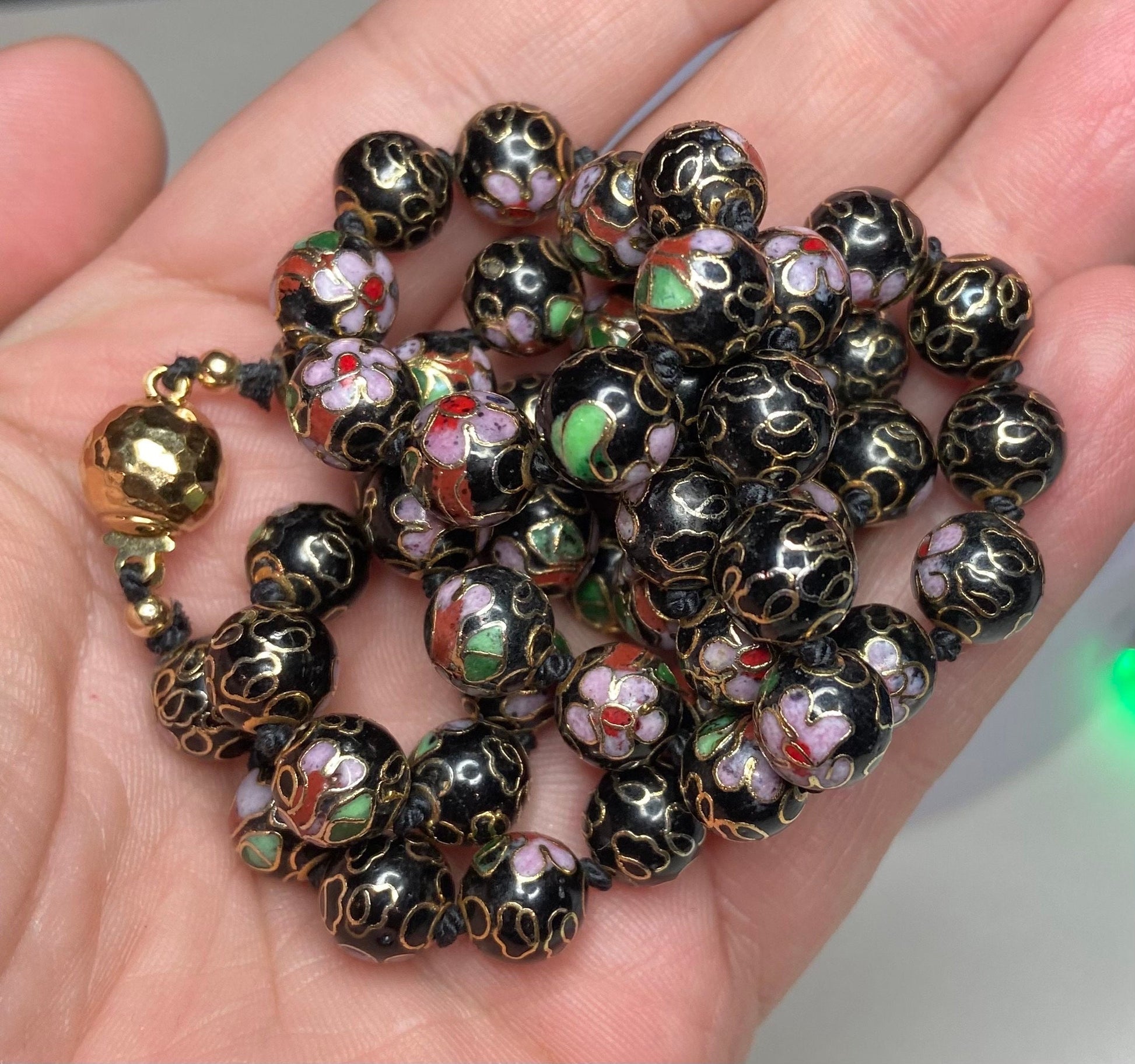 Cloisonné beaded necklace with black, pink, and gold floral designs.