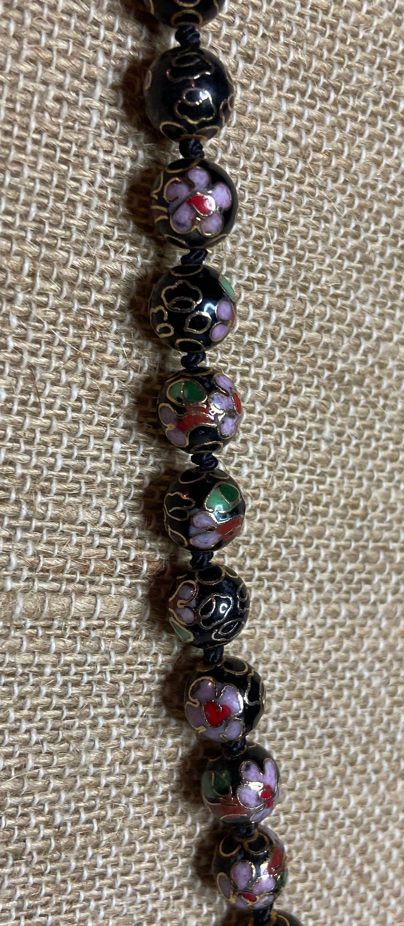 Cloisonné beaded necklace with black, pink, and gold floral designs.