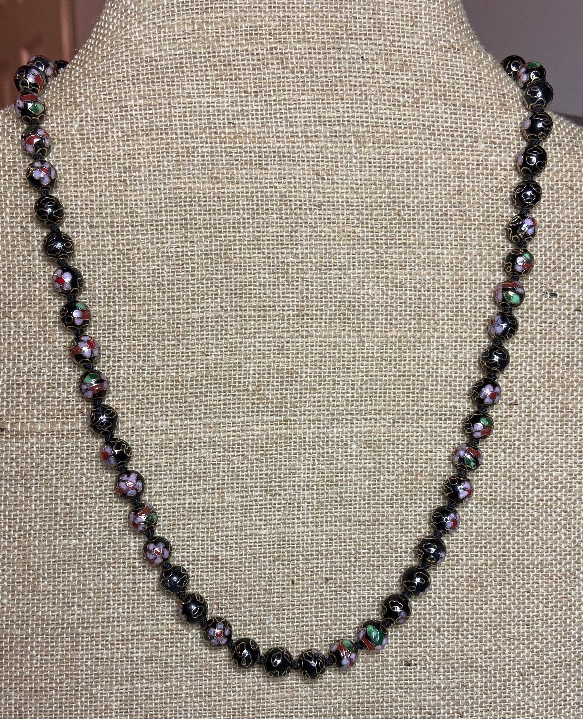 Cloisonné beaded necklace with black, pink, and gold floral designs.