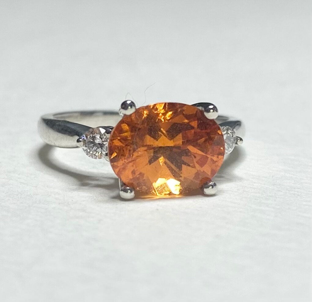 Sterling silver ring with a large oval spessartite garnet and two lab-grown diamonds.