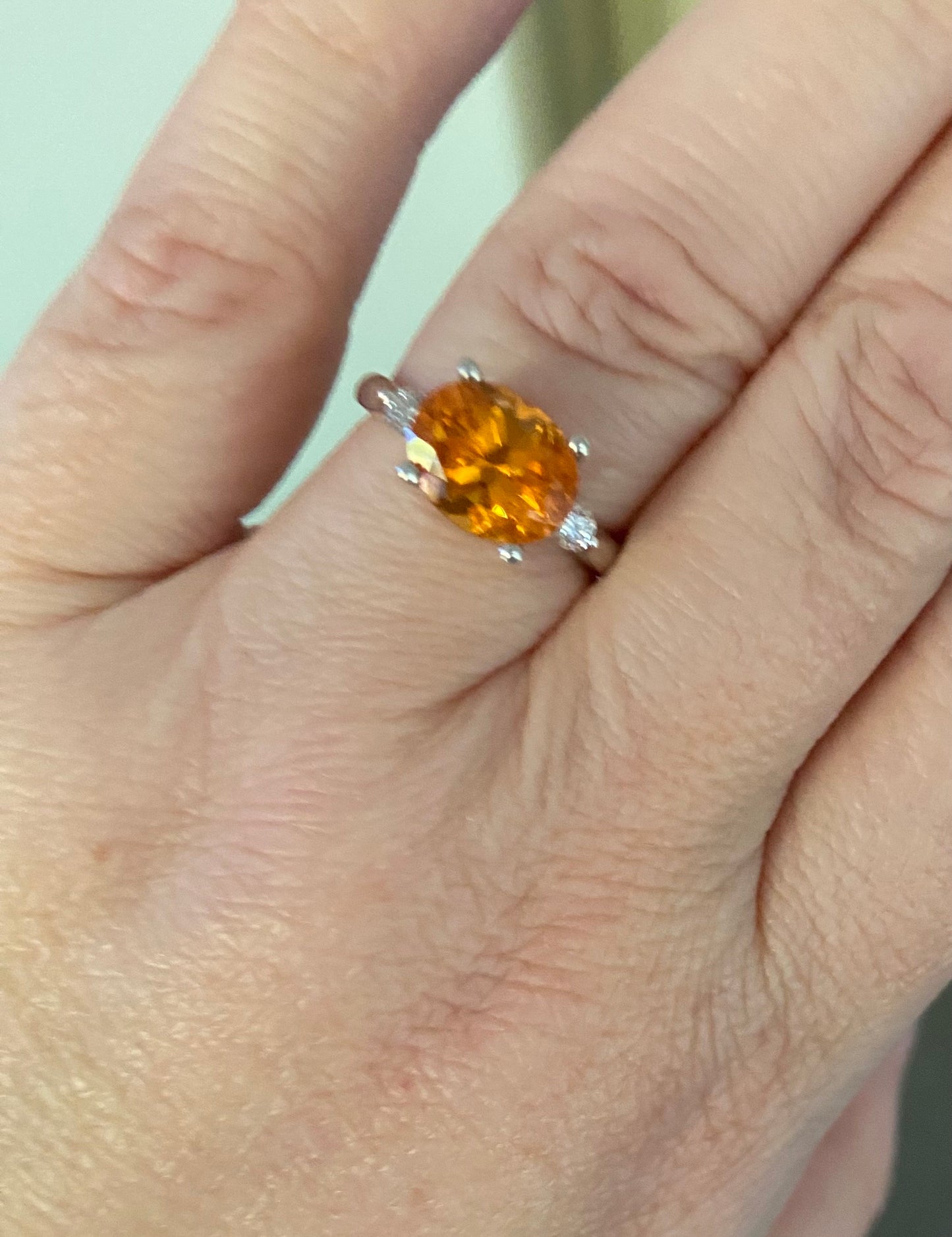 Sterling silver ring with oval spessartite garnet and two lab-grown diamonds.