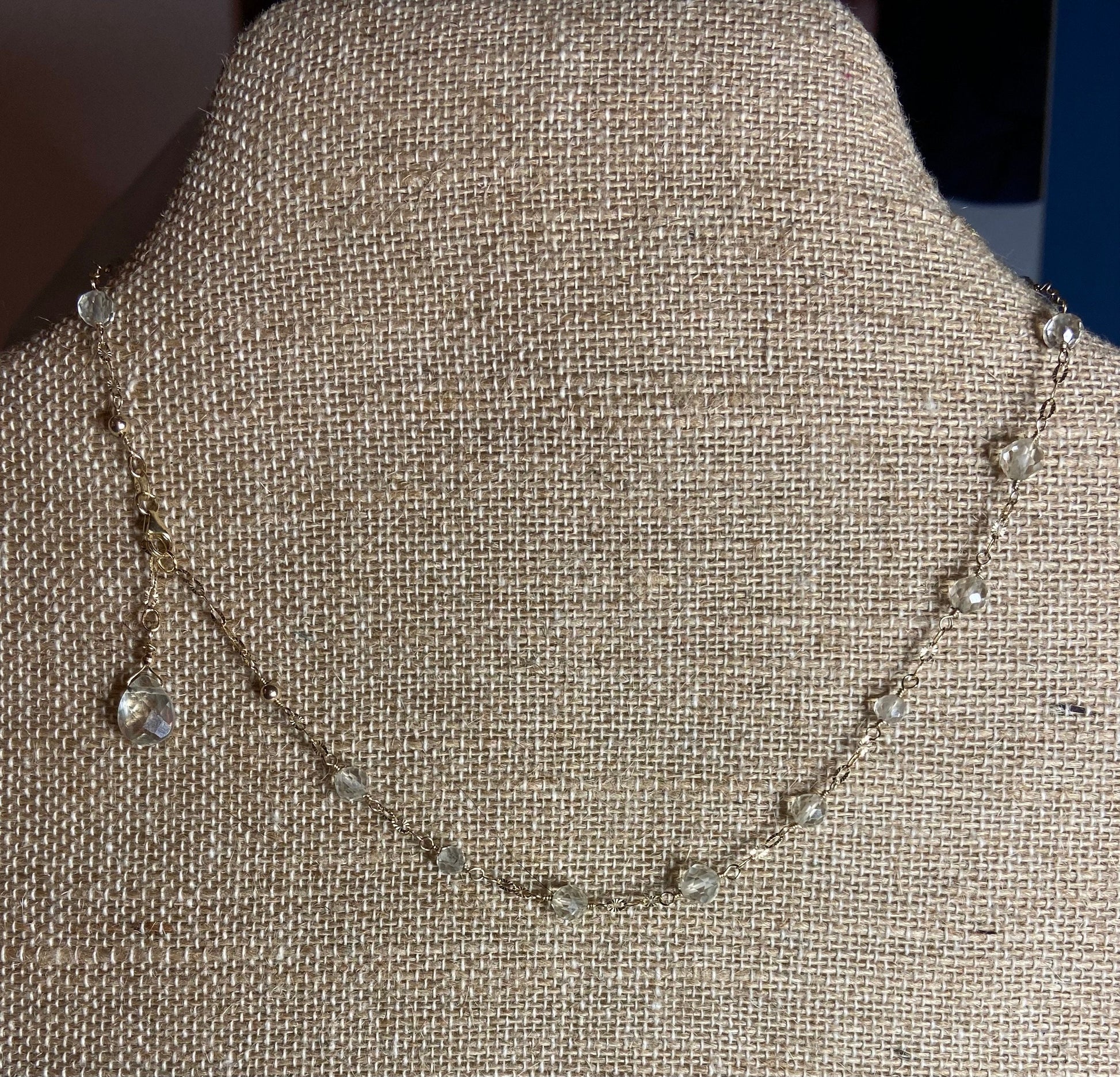 A delicate 14k yellow gold necklace with small clear beads and a teardrop pendant.