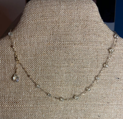 A delicate 14k yellow gold necklace with small clear beads and a teardrop pendant.