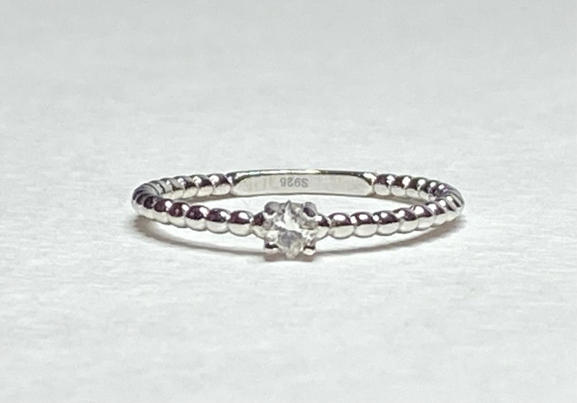 Sterling silver beaded band ring with a princess-cut diamond.