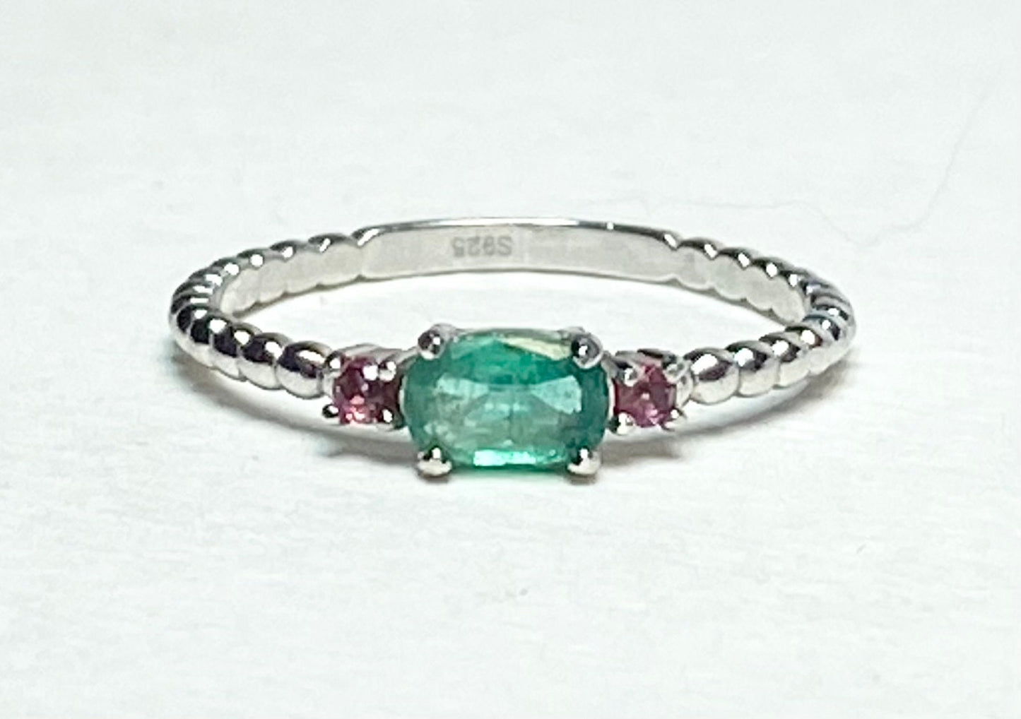 Sterling silver ring with oval emerald and two pink bixbite stones.