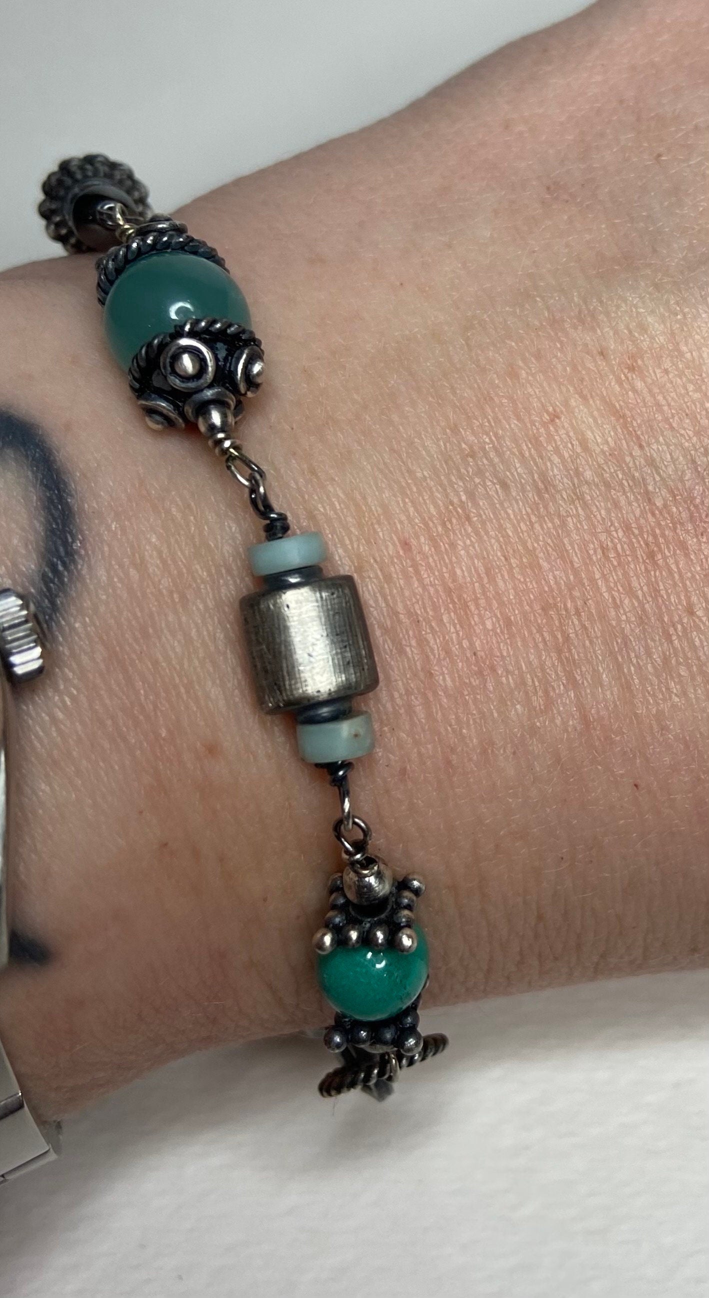 Sterling silver bracelet with green beads and cylindrical silver beads.