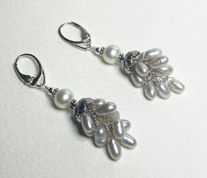 Silver dangle earrings with white and oval freshwater pearls.