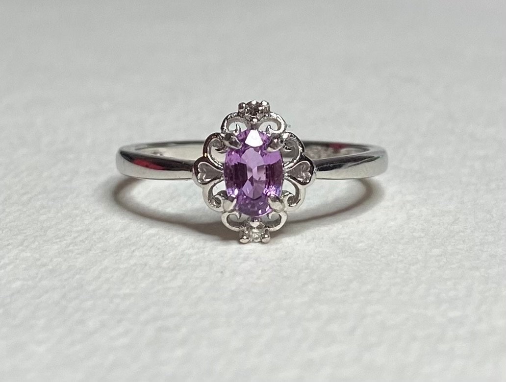 Sterling silver ring with oval pinkish-purple sapphire and diamond accents.