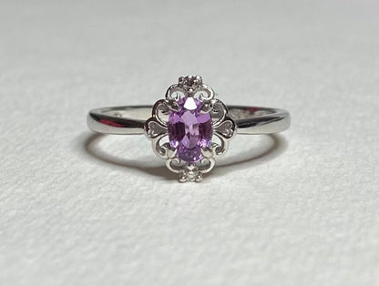 Sterling silver ring with oval pinkish-purple sapphire and diamond accents.