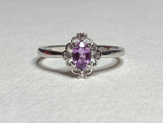 Sterling silver ring with oval pinkish-purple sapphire and diamond accents.