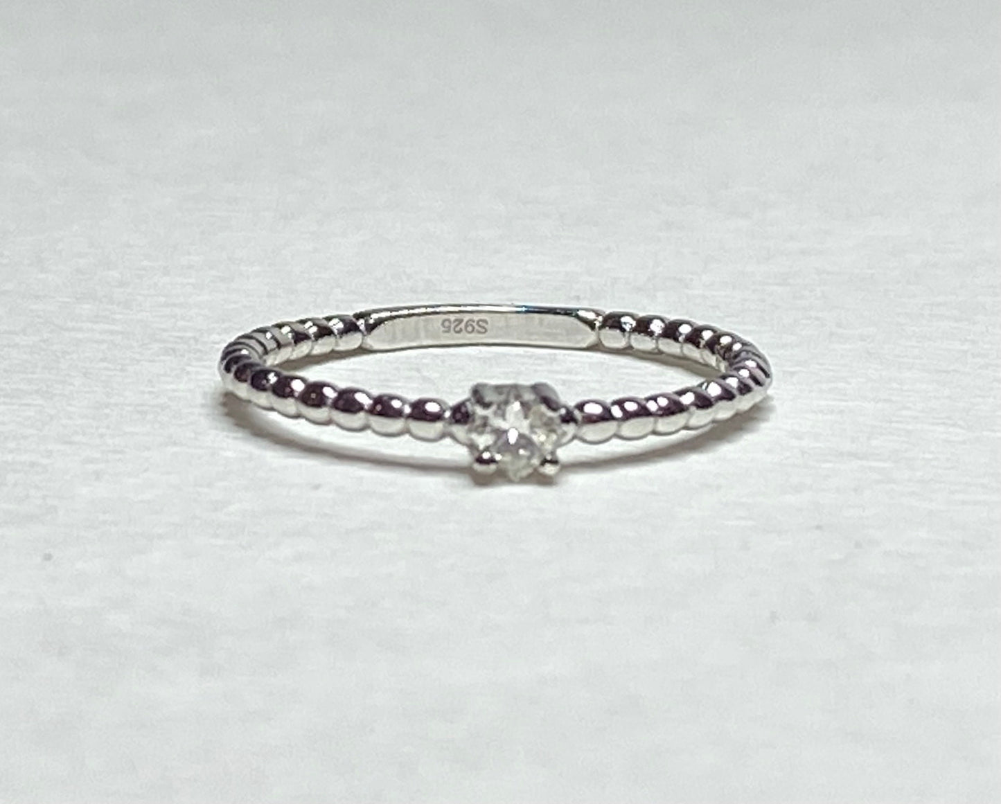 Sterling silver beaded band ring with a princess-cut diamond.