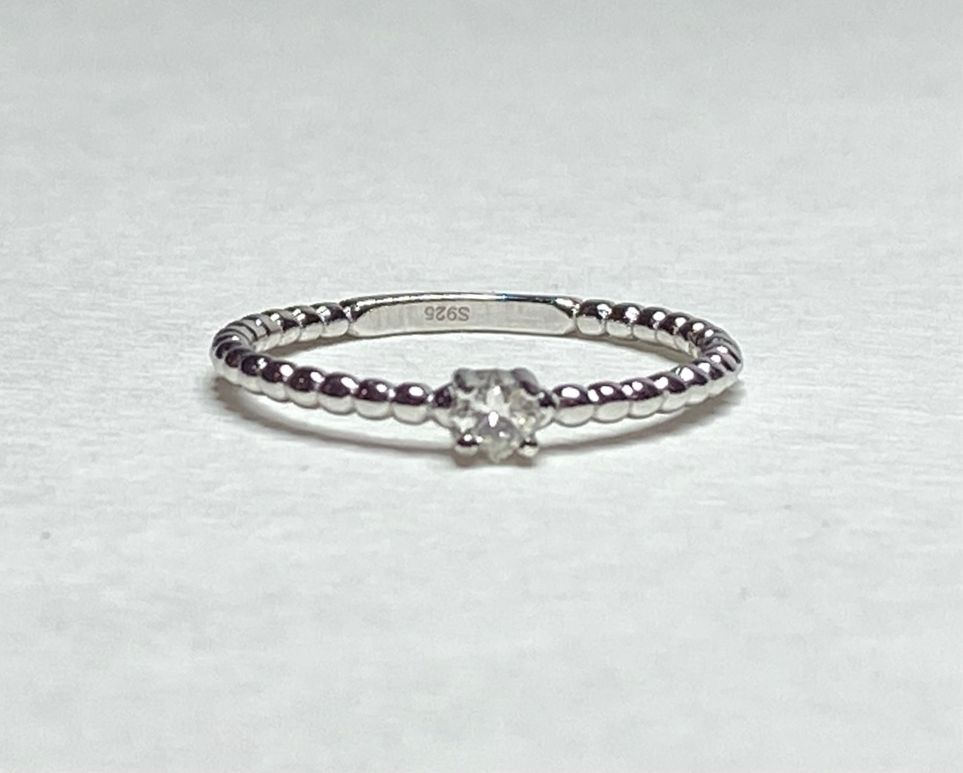 Sterling silver beaded band ring with a princess-cut diamond.