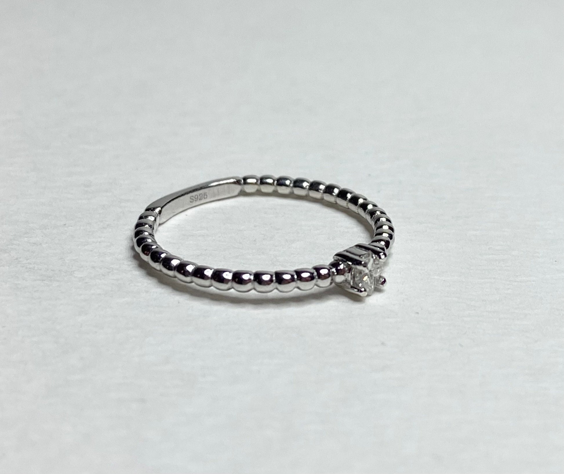 Sterling silver beaded band ring with a princess-cut diamond.