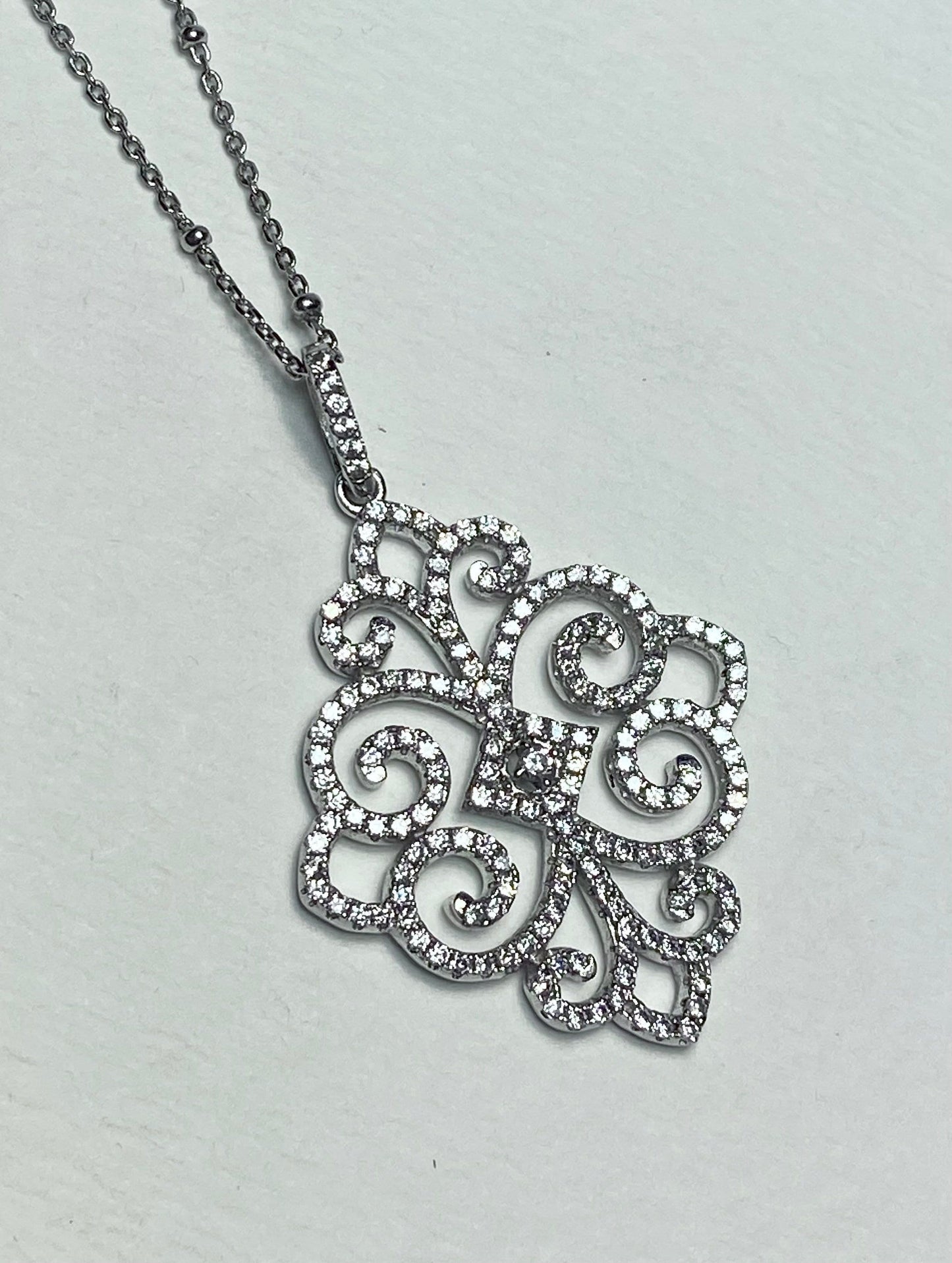 Rhodium over sterling silver pave swirl pendant necklace with cubic zirconia.