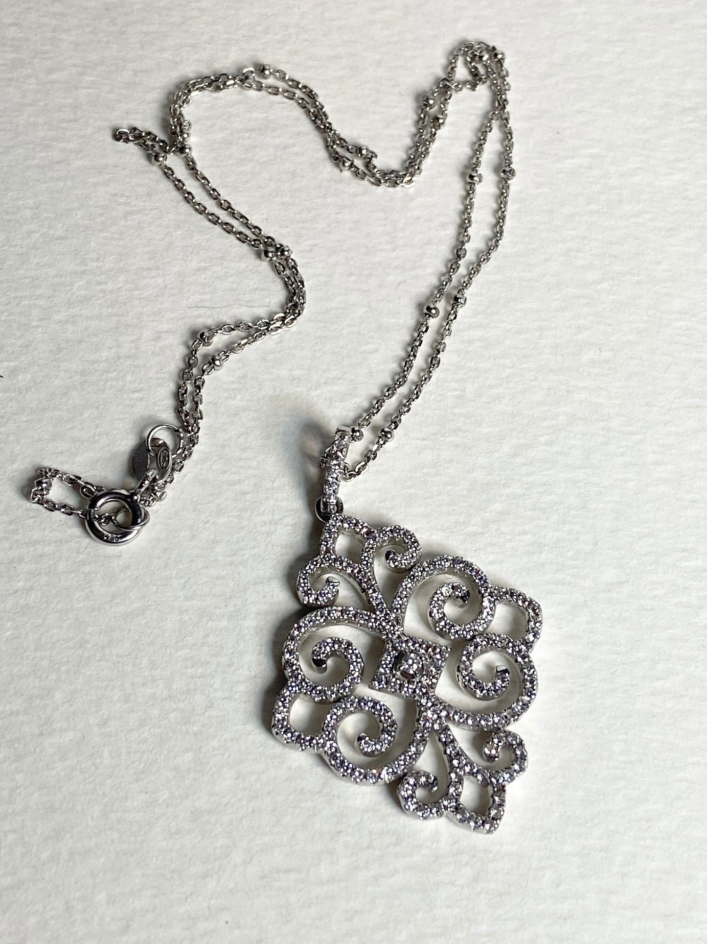 Rhodium over sterling silver pendant necklace with pave swirl design.