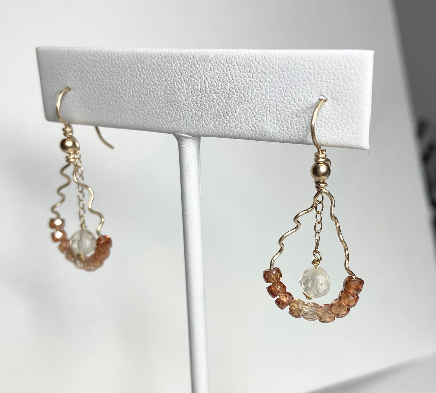 Gold dangle earrings with brown zircons and a yellow sunstone.