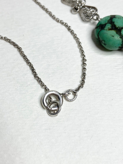 Silver chain necklace with a turquoise stone and ornate clasp.