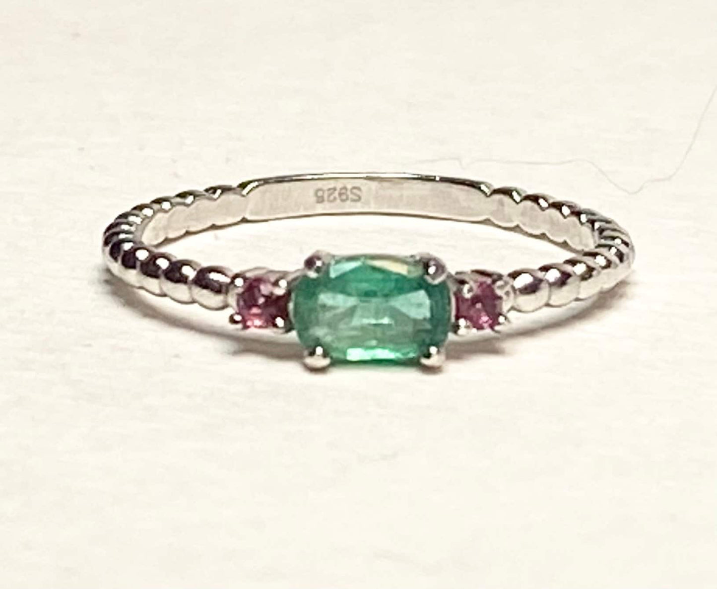 Sterling silver ring with oval emerald and two bixbite stones.