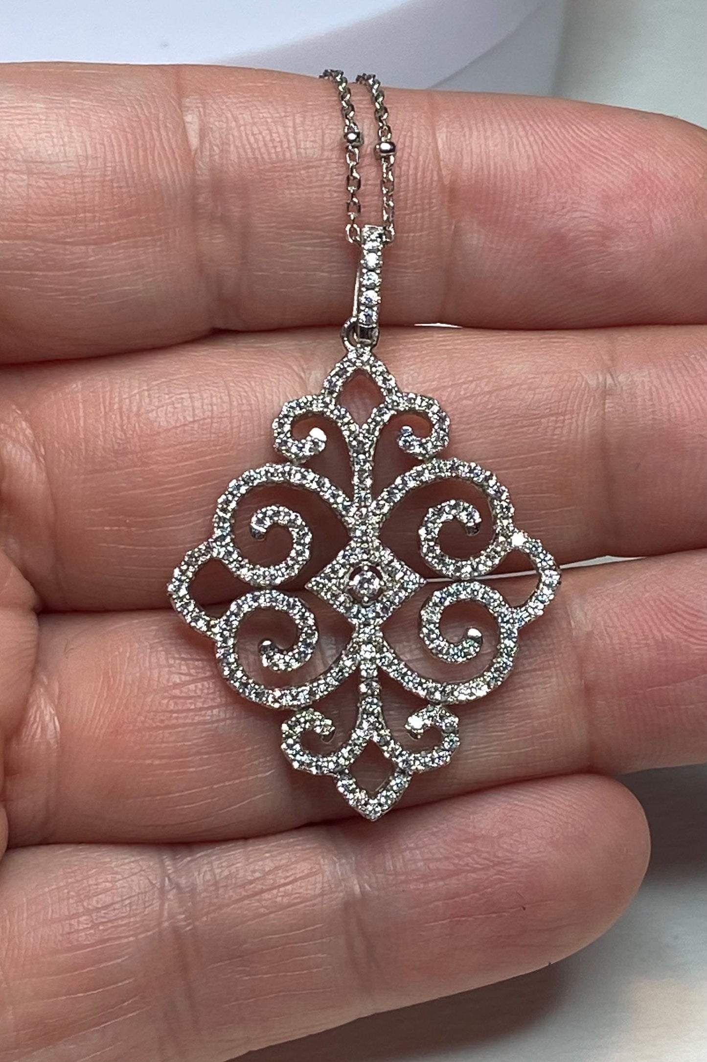 Rhodium over sterling silver pave swirl pendant necklace with a faceted curb station chain.