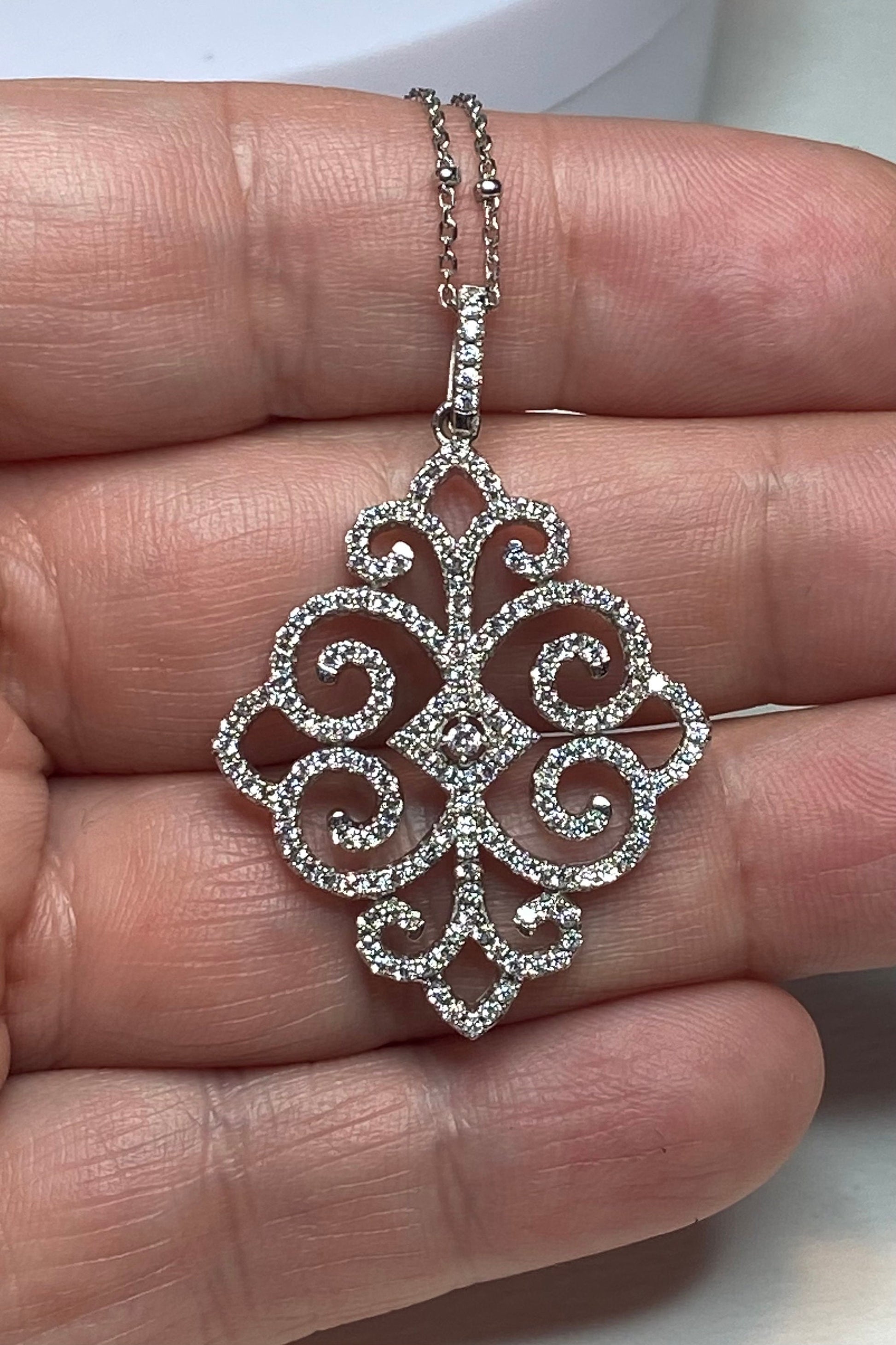 Rhodium over sterling silver pave swirl pendant necklace with a faceted curb station chain.