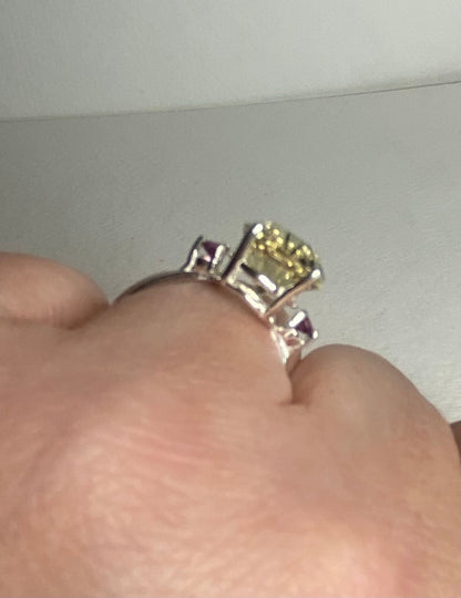 Sterling silver ring with a large yellow-green sunstone and two purple garnets.
