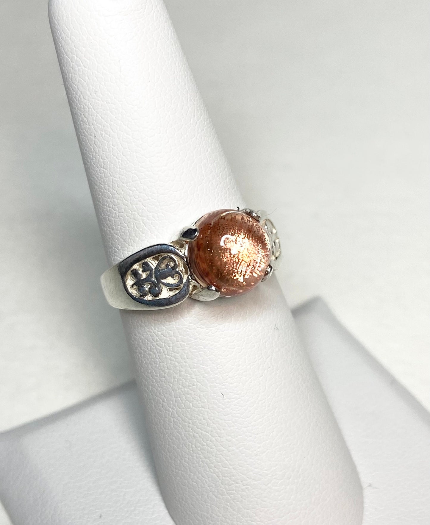 Sterling silver ring with a round Oregon sunstone cabochon and filigree band.