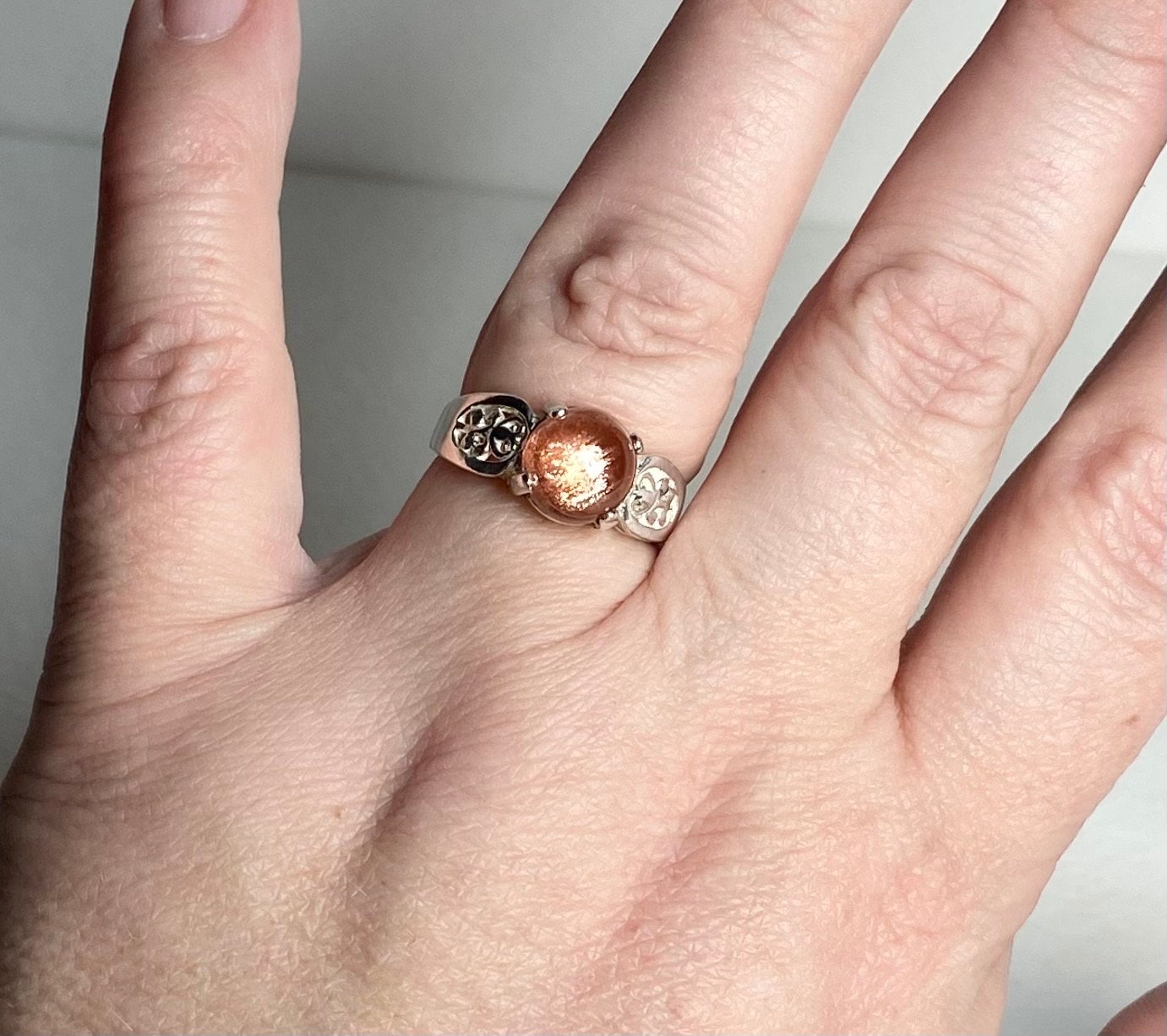 Sterling silver ring with a round Oregon sunstone cabochon and filigree details.