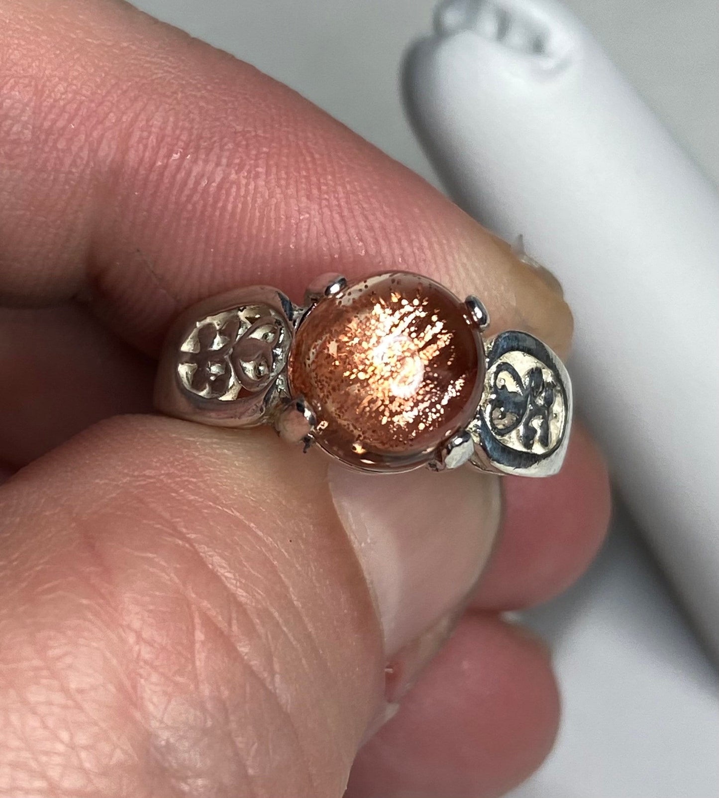 Sterling silver ring with a round Oregon sunstone cabochon and filigree band.