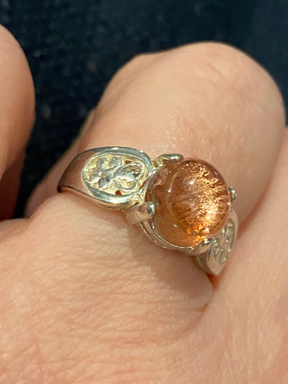 Sterling silver ring with a round Oregon sunstone cabochon and filigree band.