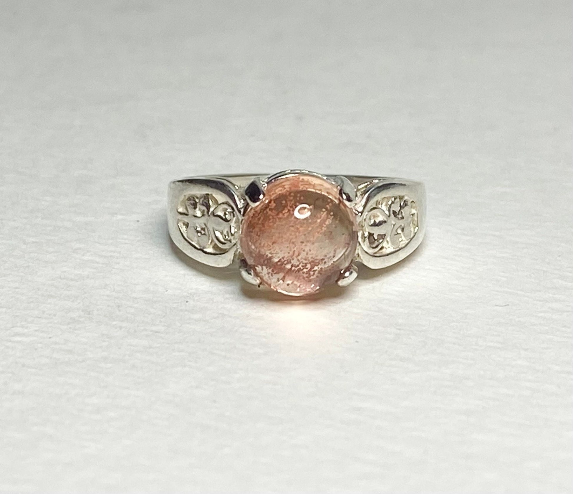 Sterling silver ring with a round Oregon sunstone cabochon and filigree band.