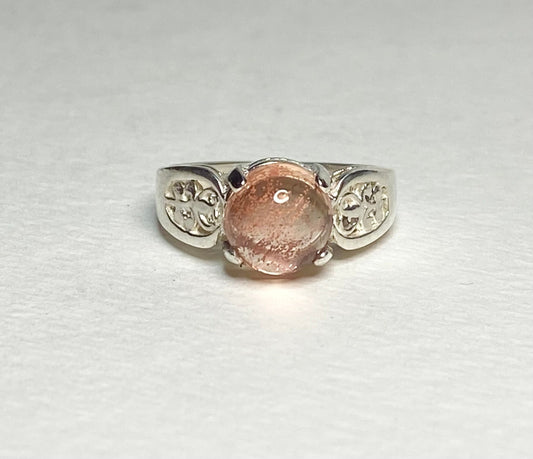 Sterling silver ring with a round Oregon sunstone cabochon and filigree band.