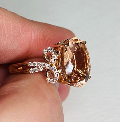 18k rose gold ring with oval morganite and diamond bow detail.