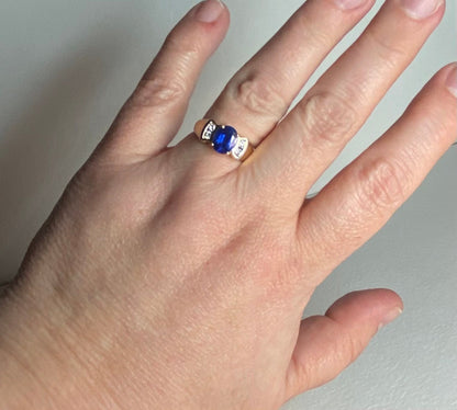 A 14k yellow gold ring with a blue sapphire and diamonds.
