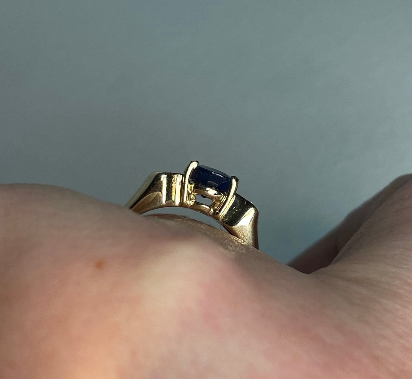 A 14k yellow gold ring with a blue sapphire and diamonds.
