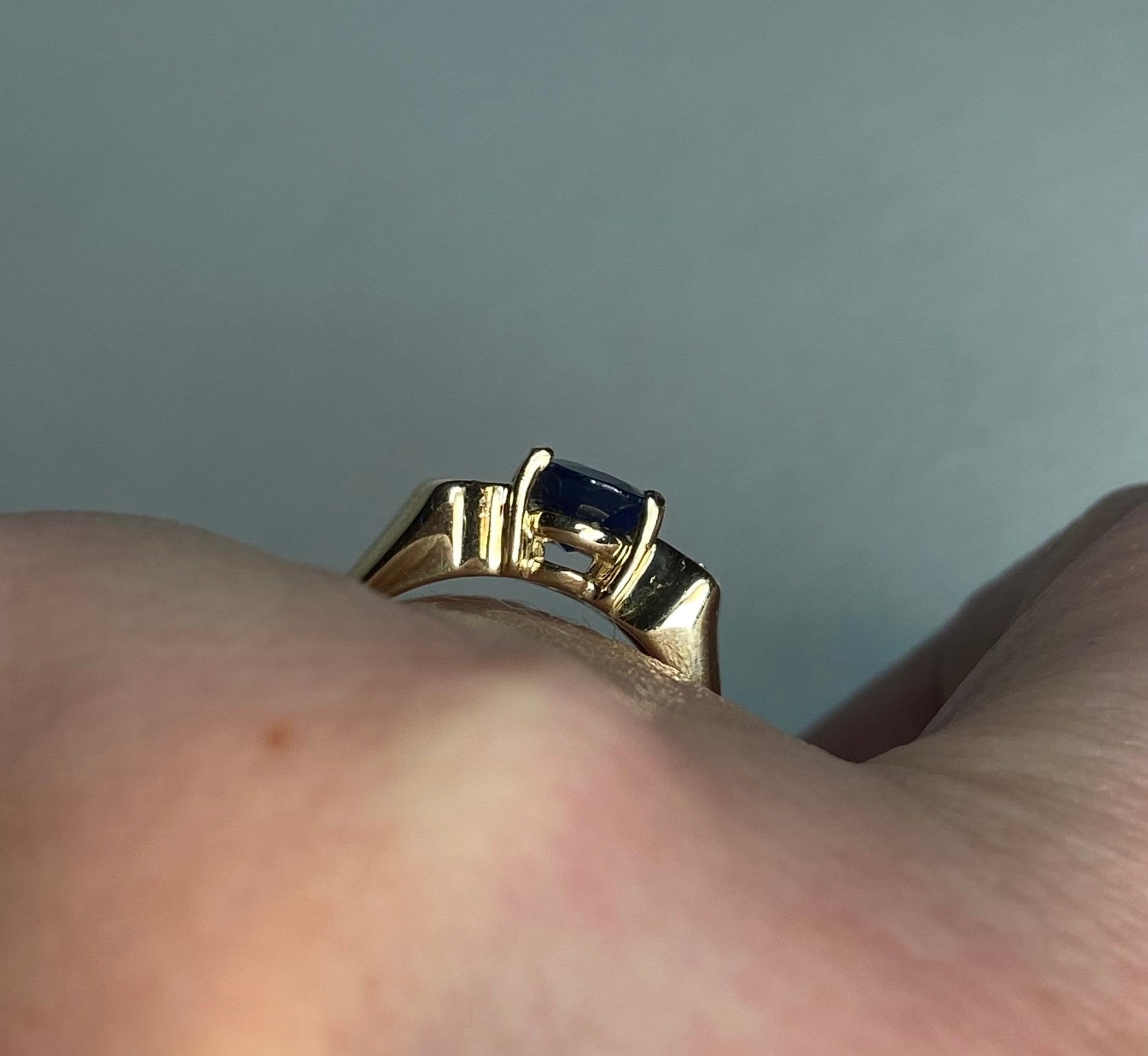 A 14k yellow gold ring with a blue sapphire and diamonds.