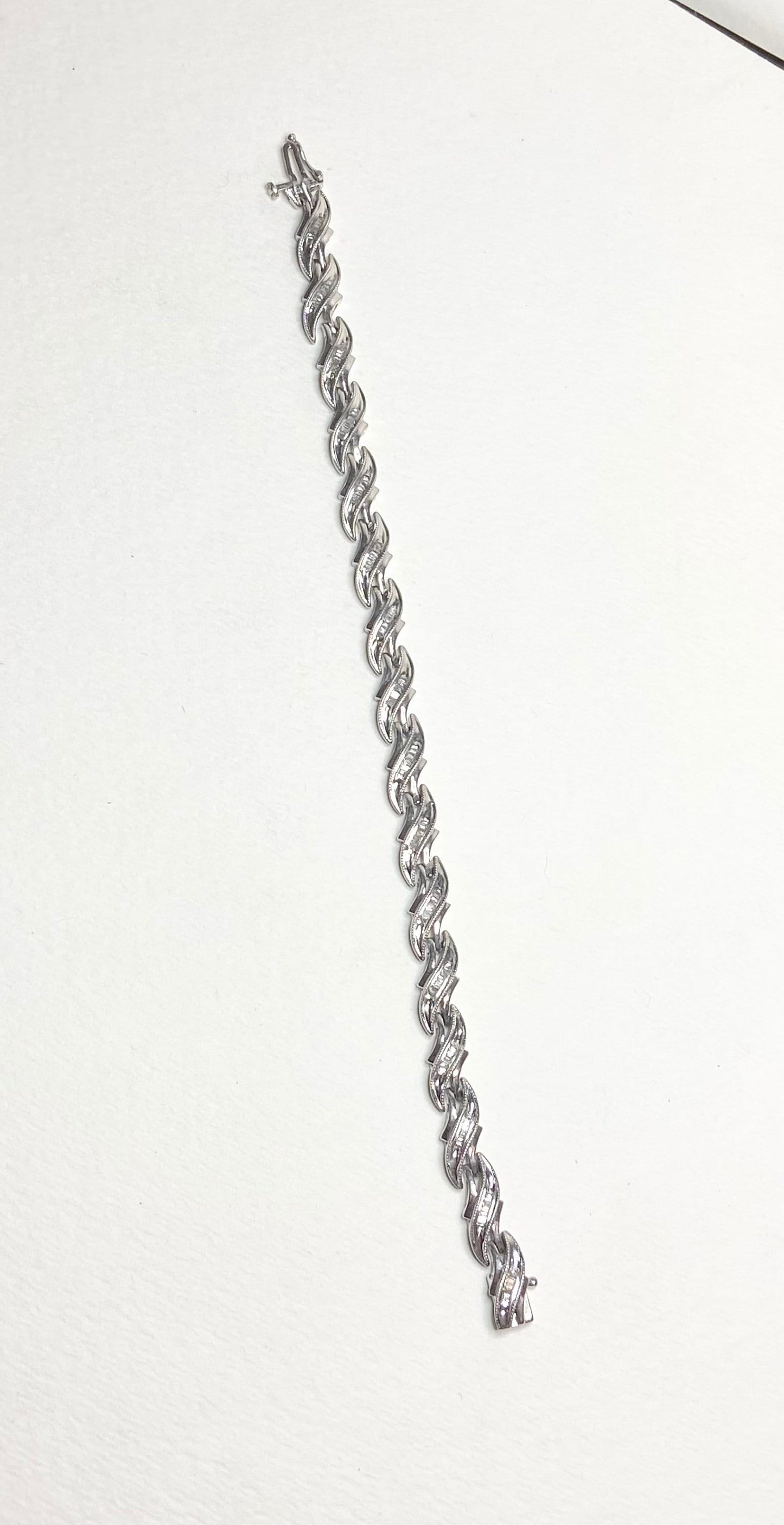 Sterling silver tennis bracelet with baguette diamonds and rhodium plating.