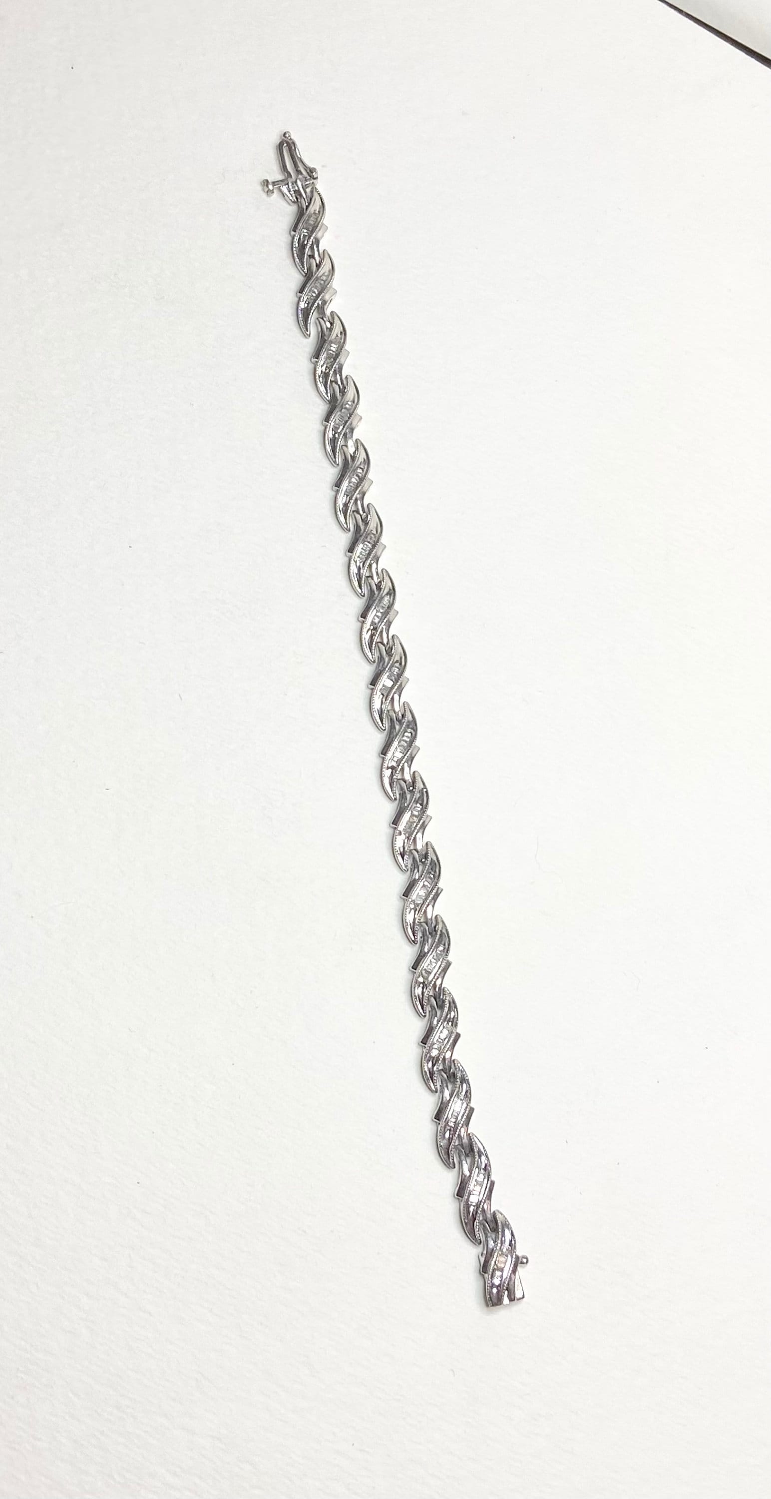 Sterling silver tennis bracelet with baguette diamonds and rhodium plating.