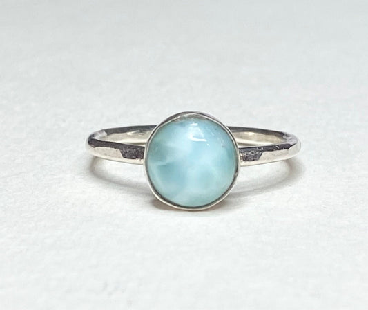 Sterling silver ring with a round, light blue larimar cabochon.