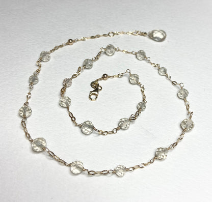 A 14k yellow gold choker necklace with light yellow faceted beads and a briolette charm.