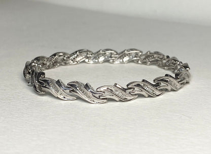 Sterling silver tennis bracelet with baguette diamonds and intricate detailing.