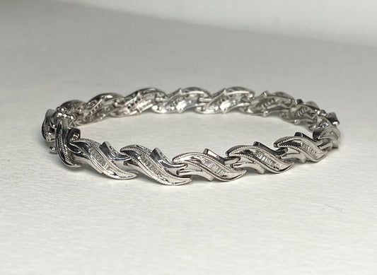 Sterling silver tennis bracelet with baguette diamonds and intricate detailing.