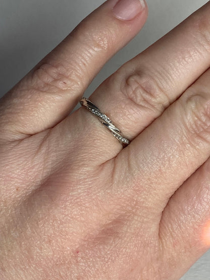A 10k white gold eternity band with a twisted design and small diamonds.