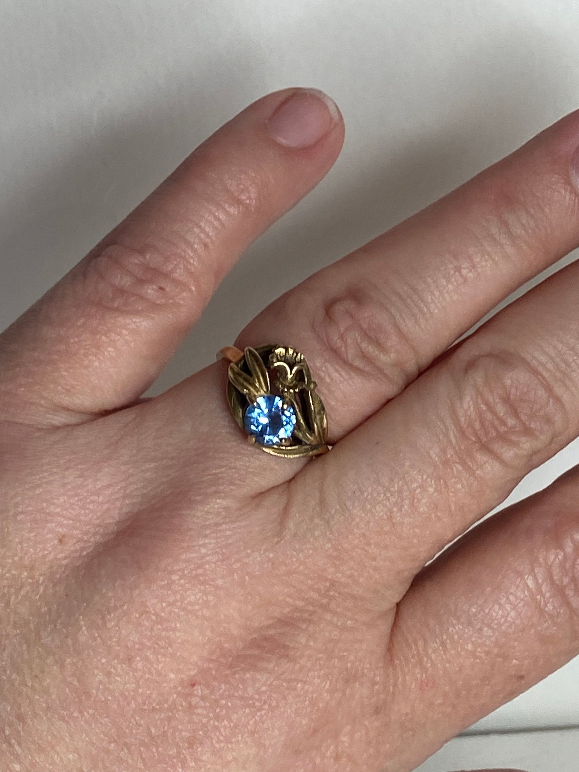 Art Nouveau style 10k yellow gold ring with a blue spinel and floral motif.