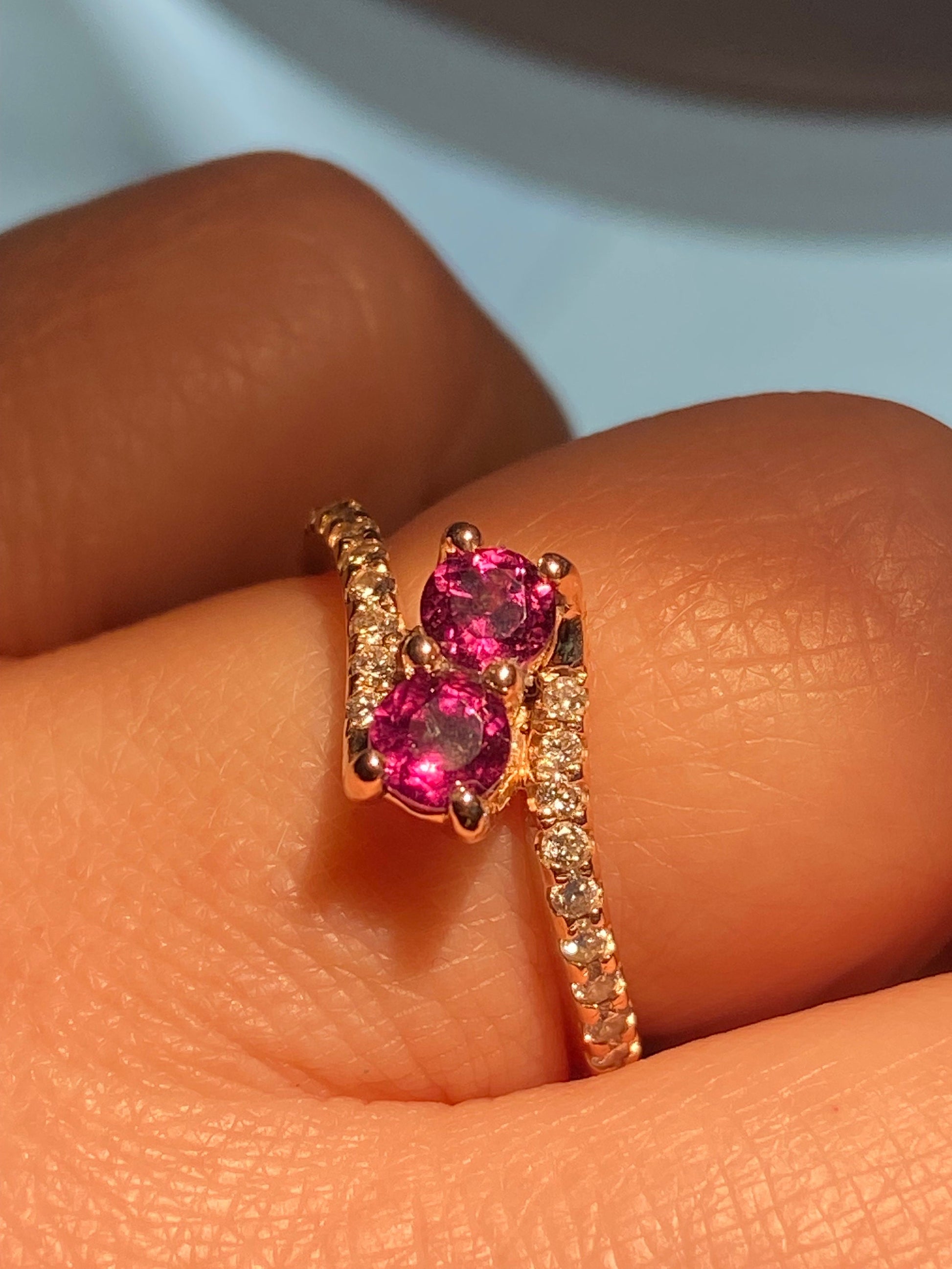 A 14k rose gold toi-et-moi ring with two rhodolite garnets and diamond accents.